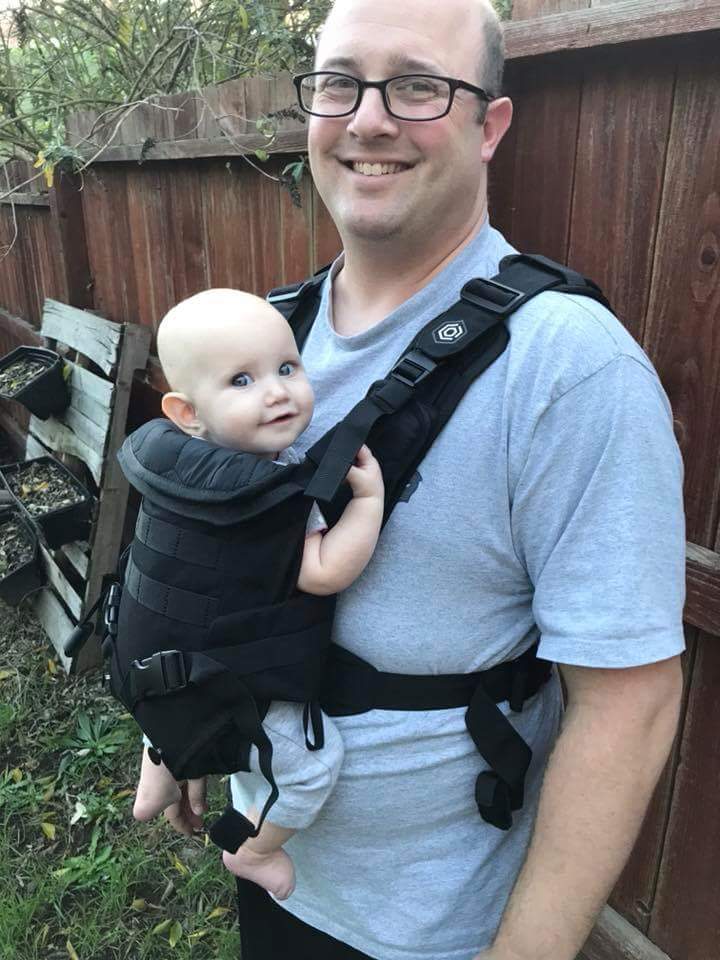 smiling dad and infant in a black Mission Critical front baby carrier